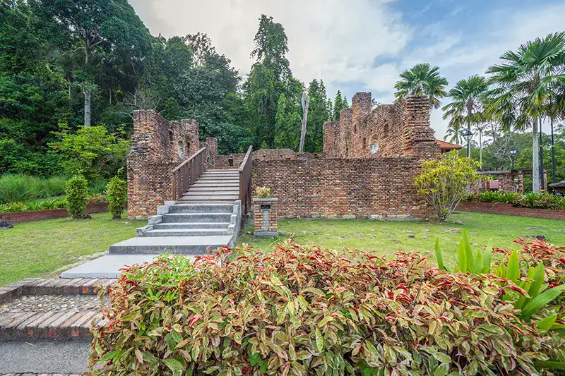 Remains of the Dutch Fort on Pangkor Island, surrounded by greenery and palm trees, showcasing colonial architecture and historical significance.