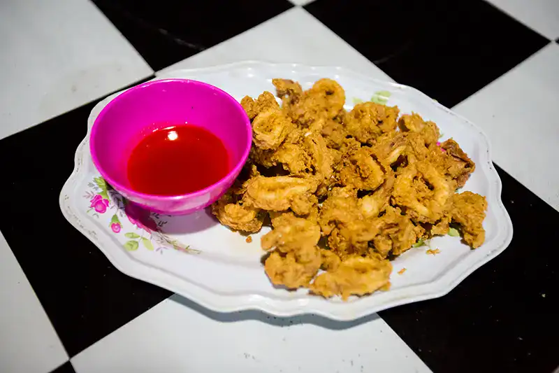 A plate of deep-fried calamari served with red dipping sauce, a popular local food dish in Pangkor Island.