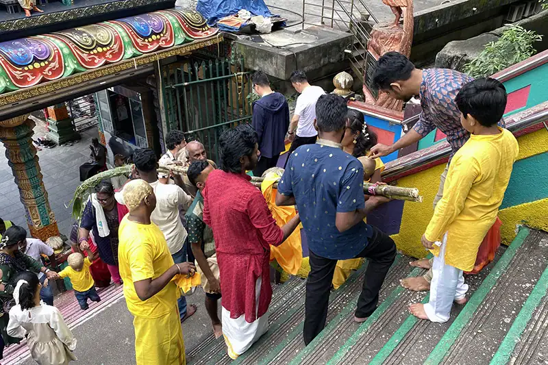 Hindu family dressed in traditional attire climbing the 272 steps at Batu Caves for a religious ceremony