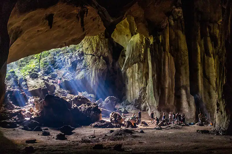 Tourists camping overnight inside a large cave during jungle trekking in Taman Negara