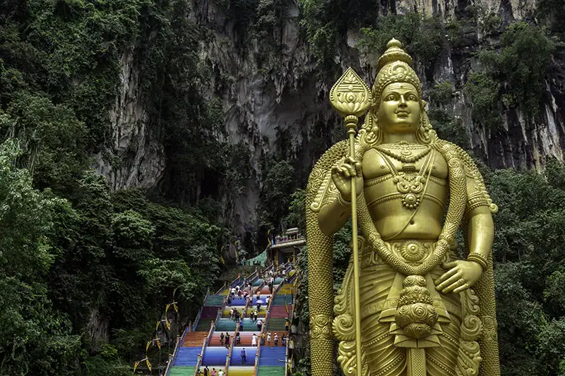 Golden Lord Murugan statue and rainbow-colored steps at Batu Caves, a popular morning stop before visiting the Malaysia Elephant Sanctuary.
