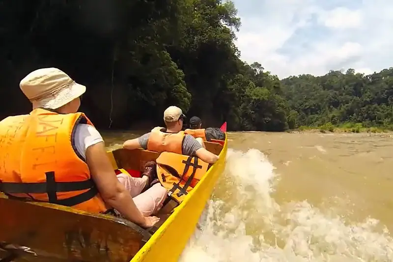 Tourists riding a longboat through rapids during a river cruise in Taman Negara