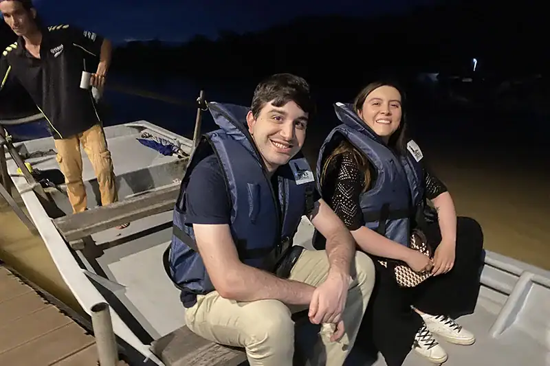 Smiling couple wearing life jackets seated in a traditional boat at Kuala Selangor Fireflies Park