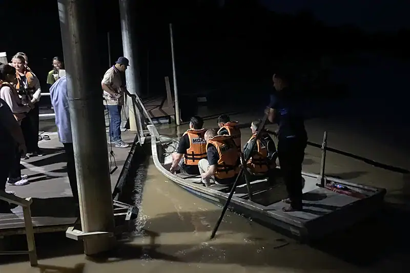 Tourists boarding a traditional sampan at Kampung Kuantan to see Kuala Selangor fireflies in their natural mangrove habitat at night.
