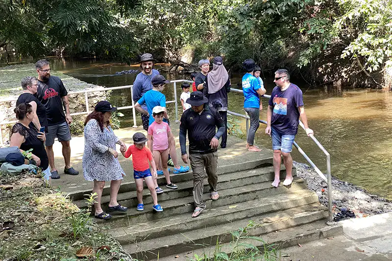 Tourists waiting by the river at Kuala Gandah Elephant Sanctuary Malaysia before bathing with baby elephants.