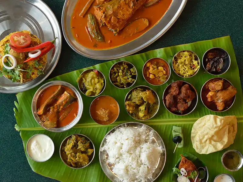 Banana leaf rice in Kuala Lumpur served with curries, vegetables, papadom and side dishes, a popular Malaysian food experience for tourists