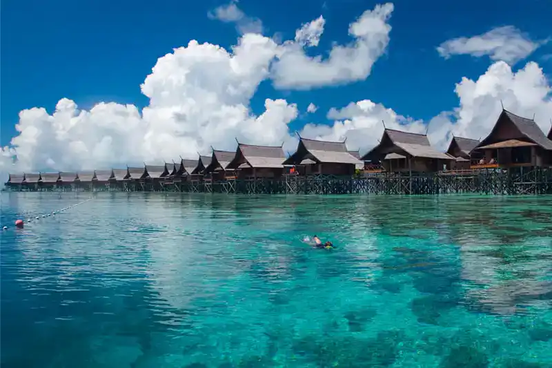 Overwater buildings along a shallow reef in a remote island setting off the coast of Borneo