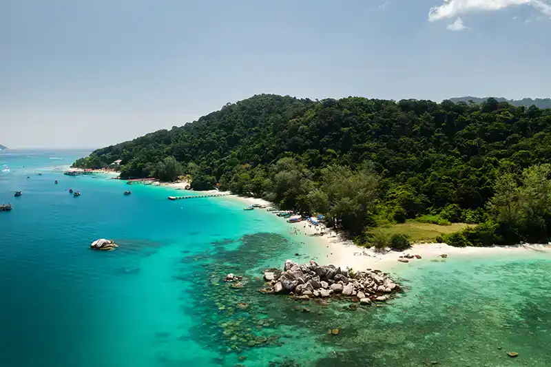 Aerial view of a tropical East Coast island in Malaysia with clear water, coral reef, and forested shoreline