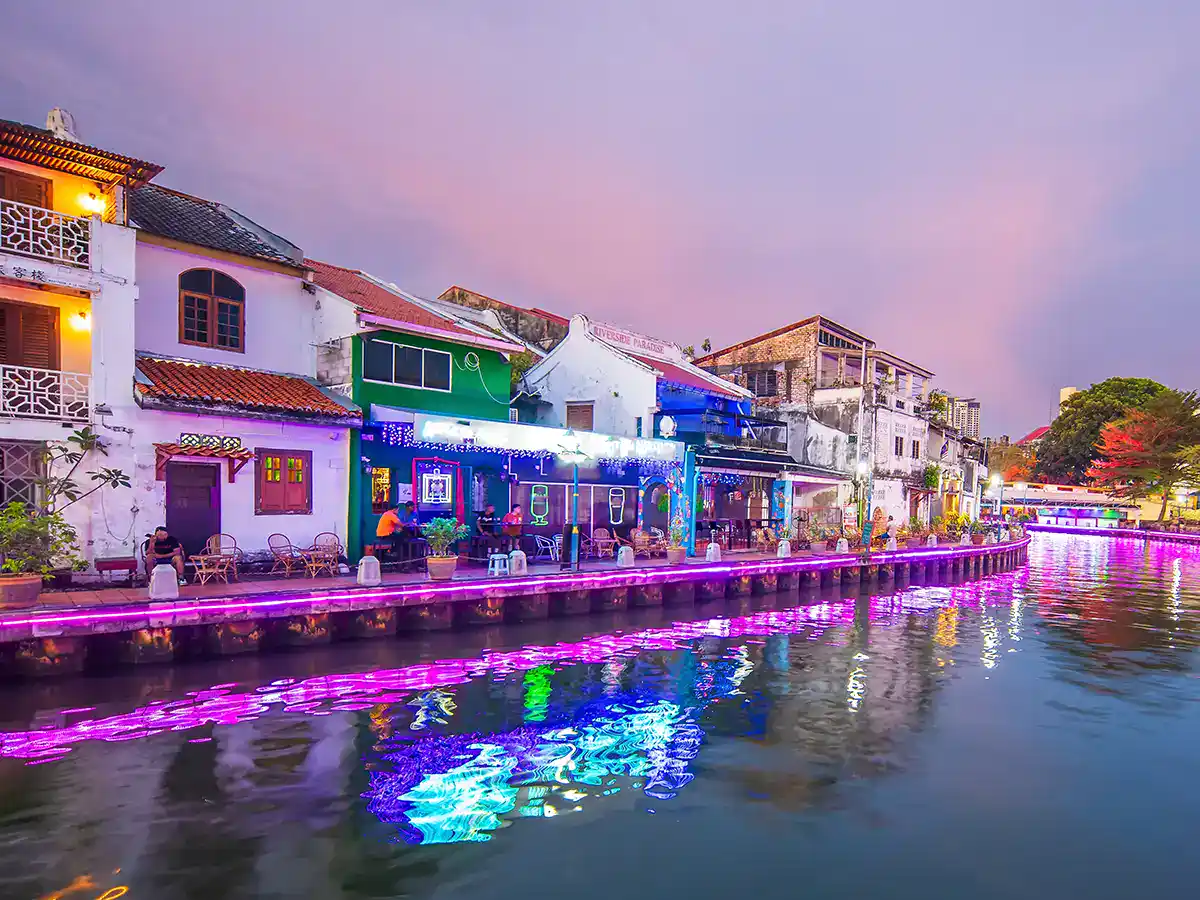 Evening atmosphere along the Malacca River with heritage buildings illuminated at night
