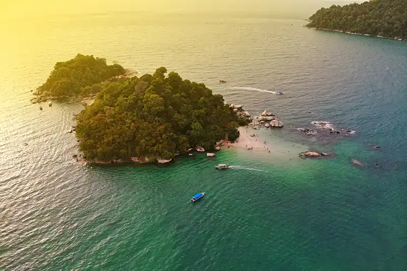 Aerial view of a small island off Malaysia’s west coast with calm water and boats near the shoreline